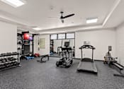 Thumbnail 2 of 42 - A spacious gym with a variety of equipment including a treadmill, weights, and a bench press.