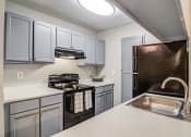 Thumbnail 4 of 24 - Flats at Riverview apartments in Duluth Georgia photo of a kitchen with white cabinets and black appliances