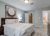 Thumbnail 5 of 24 - Flats at Riverview apartments in Duluth Georgia photo of a bedroom with a large bed and a dresser