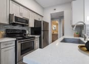 Thumbnail 1 of 20 - Apartments in Houston, TX for Rent – Gramercy Park -  an updated kitchen with stainless steel appliances and white counter tops