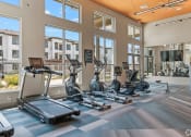 Thumbnail 31 of 43 - a gym with cardio equipment and large windows at the bradley braddock road station apartments