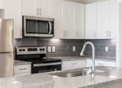 Thumbnail 17 of 43 - a kitchen with white cabinets and a granite counter top