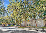 Thumbnail 16 of 16 - Greentree Apartments in Savannah, GA photo of a building with trees and cars parked in front of it