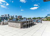 Thumbnail 18 of 21 - A rooftop patio with a stone barrier and several chairs.