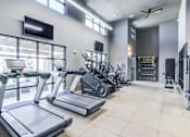 Thumbnail 7 of 17 - A gym with treadmills, elliptical machines, and a television.