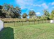 Thumbnail 58 of 63 - A black fence surrounds a grassy area with trees in the background.