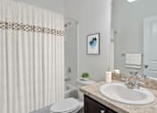 Thumbnail 55 of 63 - A bathroom with a white toilet, a sink, and a shower curtain.