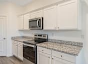 Thumbnail 40 of 63 - A kitchen with granite countertops and white cabinets.