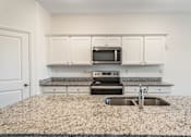 Thumbnail 39 of 63 - A kitchen with granite countertops and white cabinets.