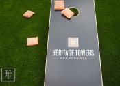 Thumbnail 39 of 40 - a tennis court with chairs on the grass and the heritage towers apartments logo