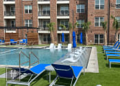 Thumbnail 40 of 40 - Heritage towers apartments an outdoor pool with lounge chairs and umbrellas in front of an apartment building lewisville tx apartments apartments near lewisville tx lewisville apartments