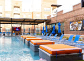 Thumbnail 6 of 40 - a resort style pool with blue chairs and orange cushions