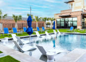 Thumbnail 4 of 40 - a swimming pool with chairs and umbrellas in front of a building