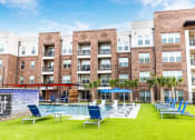Thumbnail 8 of 40 - an outdoor pool with lounge chairs and tables in front of an apartment building