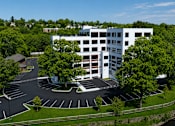 Thumbnail 17 of 25 - A white building with a parking lot in front of it.