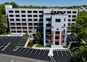 Thumbnail 16 of 25 - A modern building with a parking lot in front.