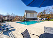 Thumbnail 14 of 17 - Pet-Friendly Apartments in Antioch, TN– Hickory Lake – A pool area with sun loungers and a building in the background.