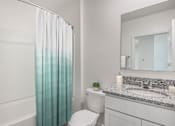 Thumbnail 32 of 35 - A white bathroom with a toilet, sink, and shower curtain.