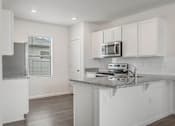 Thumbnail 16 of 35 - A kitchen with white cabinets and a granite countertop.