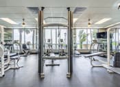 Thumbnail 12 of 23 - Horizons North Apartments near Andover, FL photo of a gym with cardio equipment and windows in the background