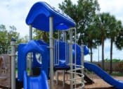 Thumbnail 11 of 23 - Horizons North Apartments near Carver Ranches, West Park, Florida photo of a blue playground with a slide and monkey bars