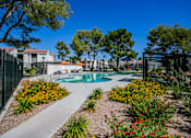Thumbnail 24 of 36 - a pool is surrounded by flowers and trees and a fence
