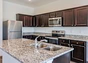 Thumbnail 54 of 75 - A kitchen with granite countertops and stainless steel appliances.