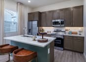 Thumbnail 12 of 47 - A kitchen with brown cabinets and a white island with a sink.