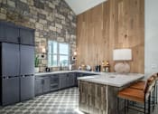 Thumbnail 32 of 47 - A kitchen with a stone wall and wooden paneling.