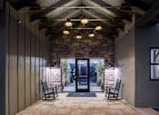 Thumbnail 28 of 47 - A stone wall with a glass door and two green chairs.