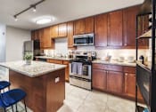 Thumbnail 1 of 27 - A kitchen with wooden cabinets and a granite countertop.