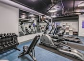 Thumbnail 25 of 27 - A gym with a variety of equipment including dumbbells, weight machines, and a treadmill.