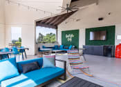 Thumbnail 16 of 33 - a patio with blue couches and chairs and tables and a tv