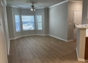 Thumbnail 12 of 25 - an empty living room with wood floors and a ceiling fan