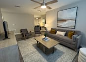 Thumbnail 10 of 29 - Twin Oaks Apartments in Hattiesburg Mississippi A living room with a grey couch, a coffee table, and a painting on the wall.