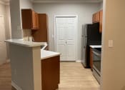 Thumbnail 11 of 25 - an empty kitchen with wooden cabinets and a black refrigerator