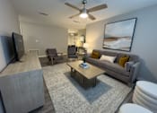 Thumbnail 8 of 29 - Twin Oaks Apartments in Hattiesburg Mississippi living room with a grey couch, a wooden coffee table, and a ceiling fan.