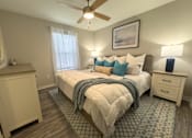 Thumbnail 11 of 29 - Twin Oaks Apartments in Hattiesburg Mississippi A bedroom with a bed, dresser, and ceiling fan.