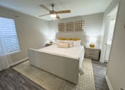 Thumbnail 13 of 29 - Twin Oaks Apartments in Hattiesburg Mississippi A bedroom with a large bed and a ceiling fan.