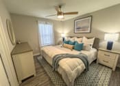 Thumbnail 15 of 29 - A bedroom with a large bed, a ceiling fan, and a nightstand.