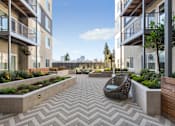 Thumbnail 16 of 20 - A modern courtyard with a woven chair and planters.