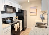 Thumbnail 2 of 35 - A kitchen with black appliances and white cabinets.