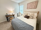 Thumbnail 9 of 35 - A bedroom with a bed, nightstand, and lamp.