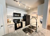 Thumbnail 1 of 35 - A kitchen with black appliances and granite countertops.