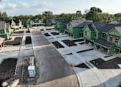 Thumbnail 6 of 14 - A construction site with green houses and a road in the foreground.