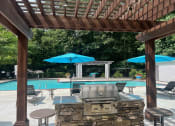 Thumbnail 14 of 27 - Place at Midway Douglasville GA a pergola with a grill and umbrellas overlooking a swimming pool