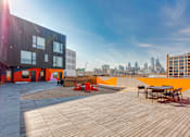 Thumbnail 13 of 29 - A modern building with a wooden deck and orange accents.