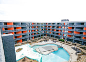 Thumbnail 30 of 51 - A large swimming pool in the middle of a courtyard surrounded by orange and grey buildings.