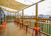 Thumbnail 45 of 51 - A wooden deck with orange stools and a yellow canopy.