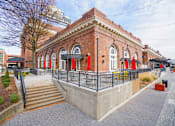 Thumbnail 49 of 51 - A red brick building with a black fence and stairs leading up to it.